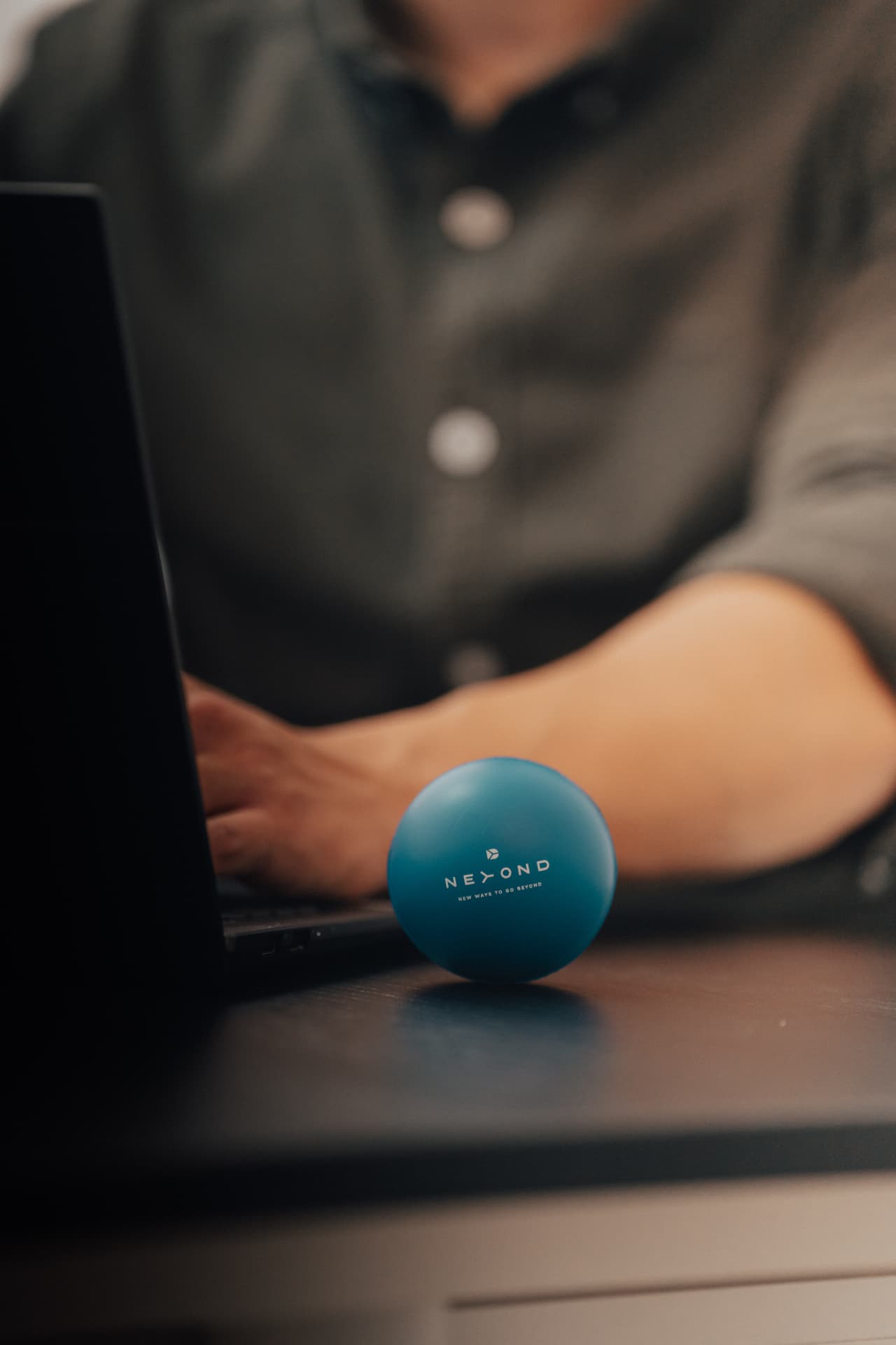 Blue Beyond branded stress ball on a desk beside a laptop
