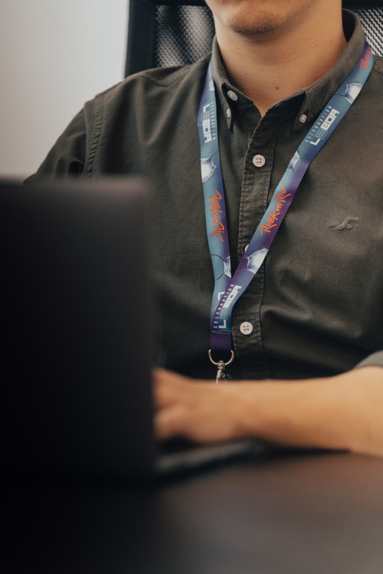 Person wearing a full-colour Rock in Rio Lisboa printed lanyard at a desk