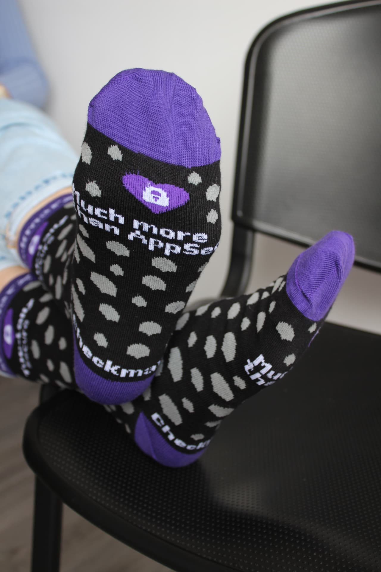 Purple and black Checkmarx branded socks worn on a chair