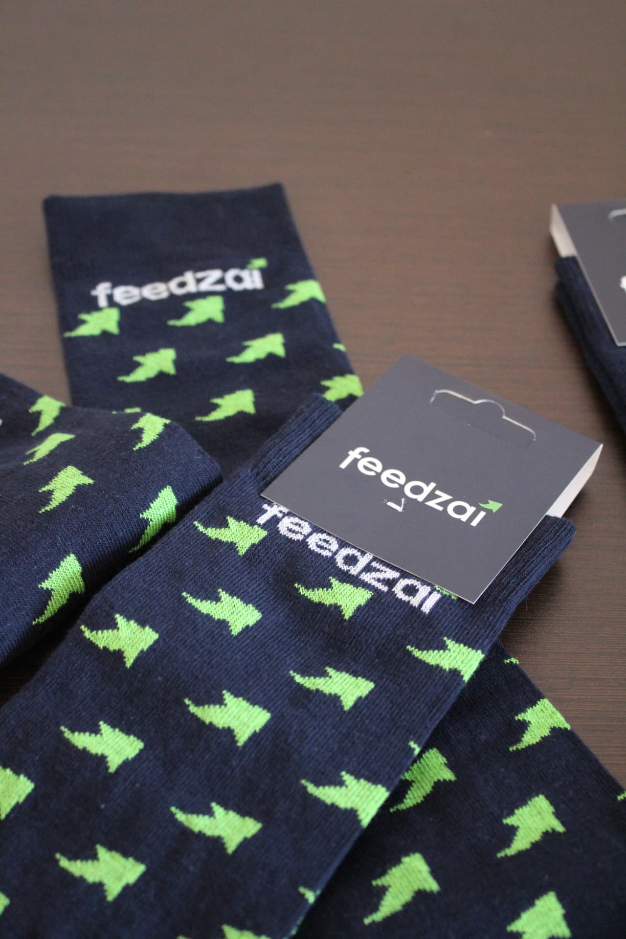 Navy Feedzai branded socks with green arrow pattern and branded hang tags