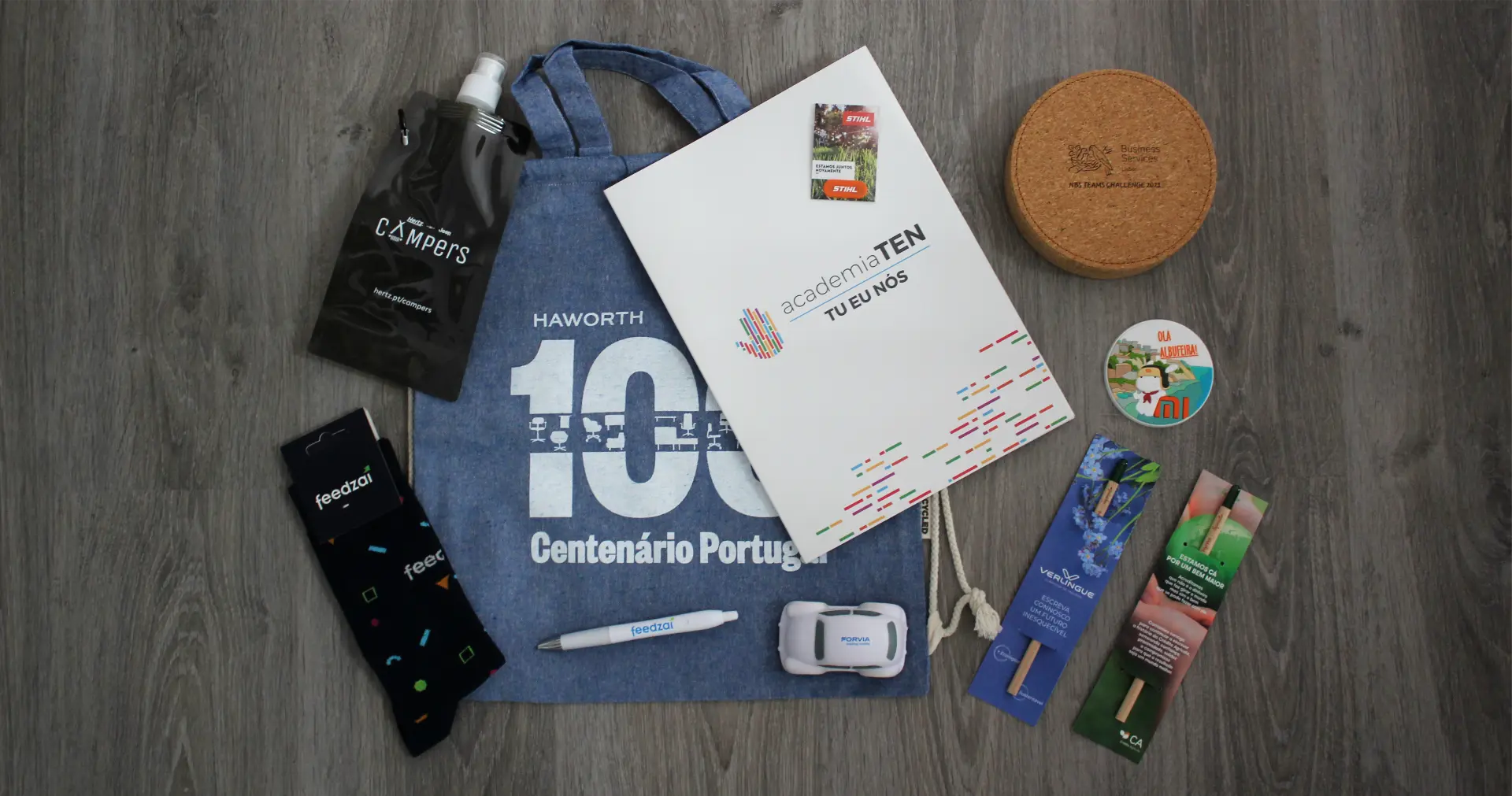 Flat lay of branded tote bag, socks, pen, notebook, cork coaster and seed sticks