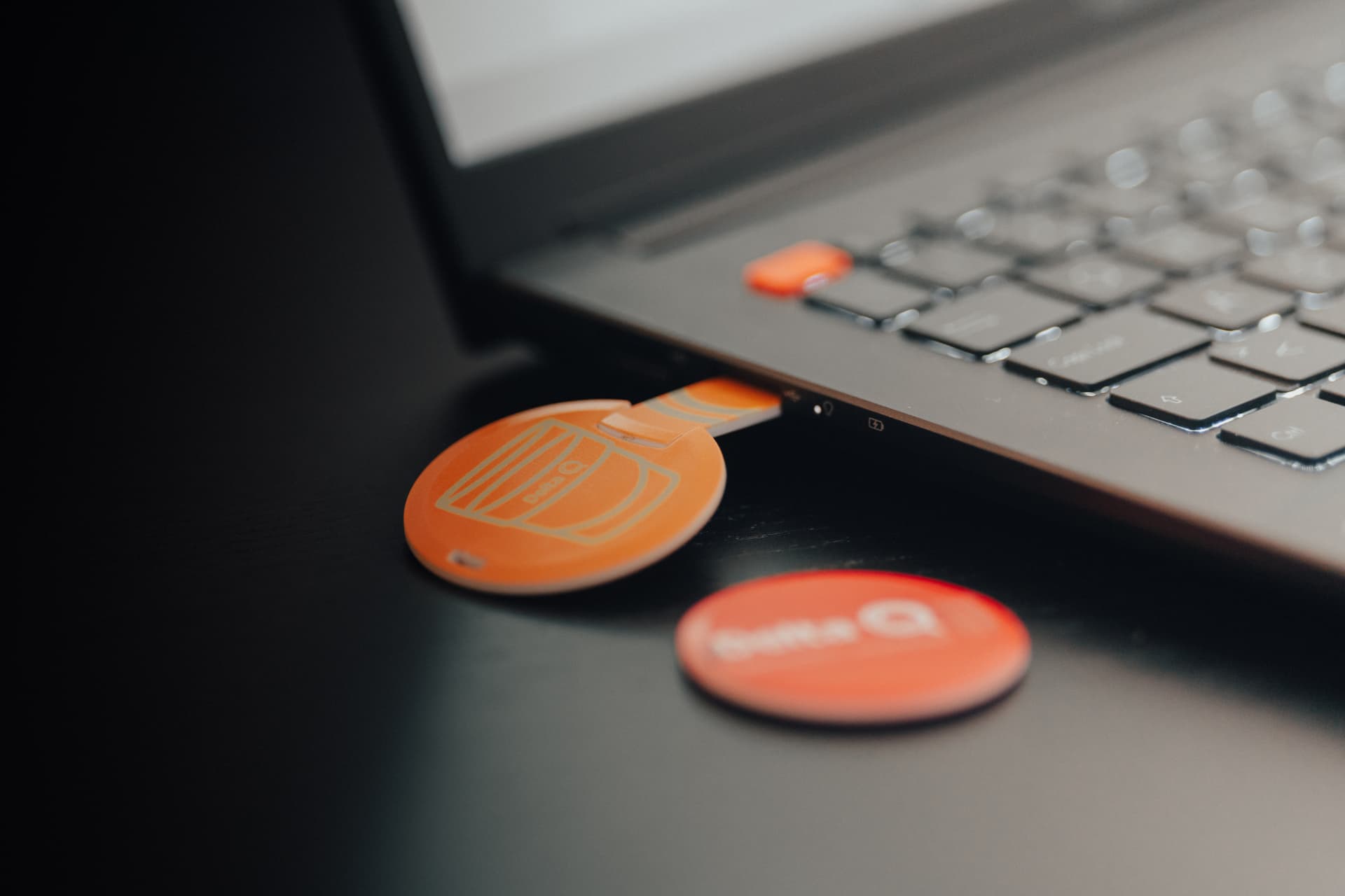 Round orange branded card USB drives beside a laptop